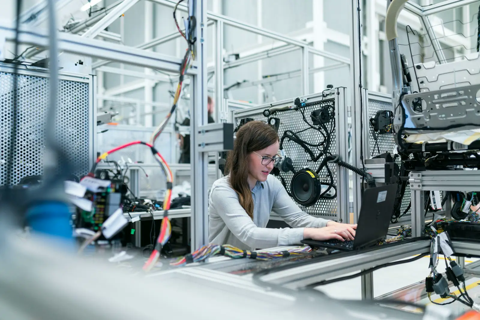 Ingénieure programmant une cellule de production automatisée sur un ordinateur portable
